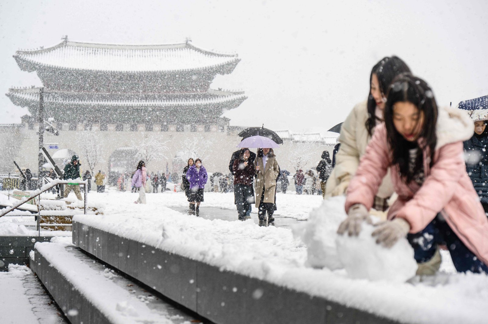 Pedestrians walk in front of the Gyeongbokgung Palace amid heavy snowfall in central Seoul, South Korea, Nov. 27, 2024. (AFP Photo)