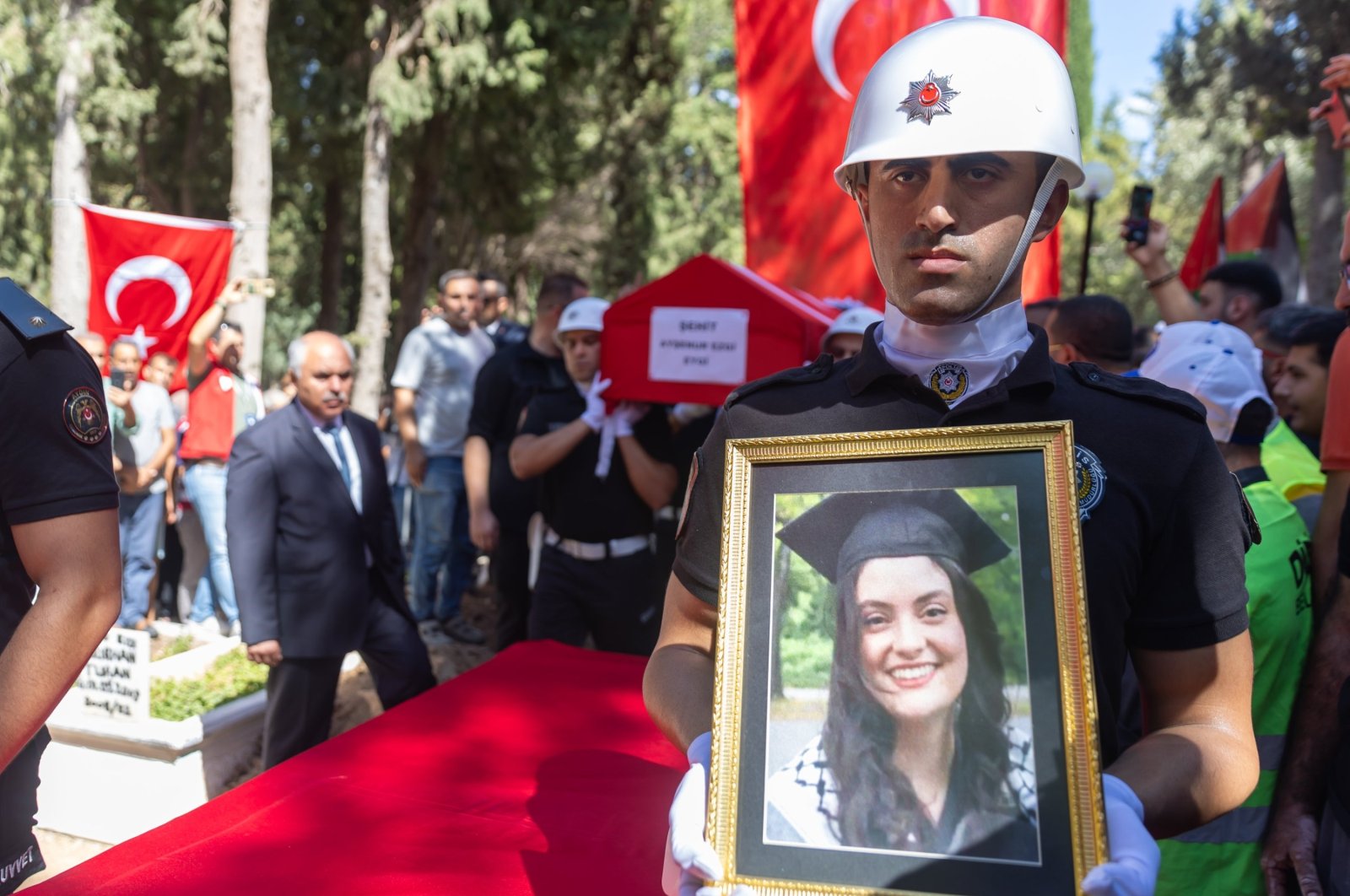 A police officer holds a portrait of Ayşenur Ezgi Eygi during her funeral procession at a cemetery in Didim, Aydın, Türkiye, Sept. 14, 2024. (AA Photo)