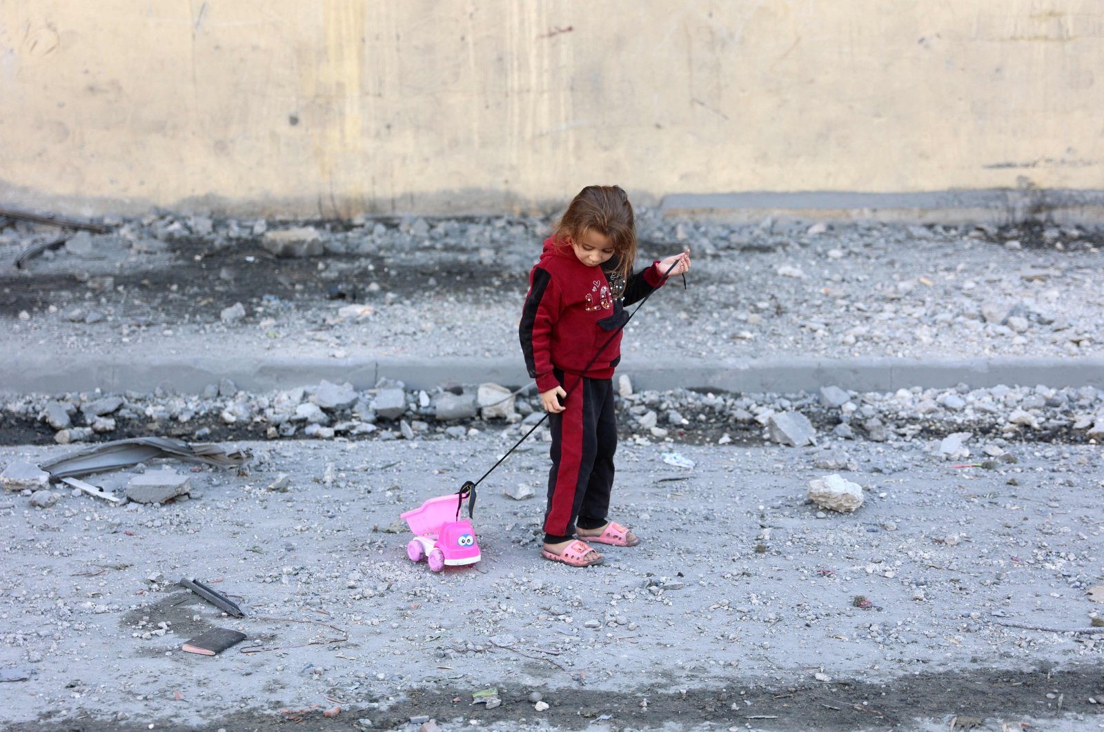 A Palestinian girl pull on her toy on a debris-filled street in Jabalia, northern Gaza, Palestine, Nov. 20, 2024. (AFP Photo)