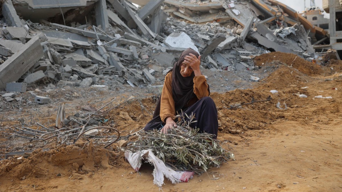 An elderly woman sits in front of a destroyed building to rest as she collects tree branches to light a fire in Nuseirat, Gaza Strip, Palestine, Nov. 29, 2024. (AFP Photo)