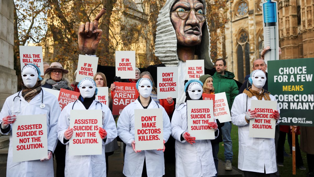 Protestors hold placards as they gather outside the Parliament as British lawmakers debate the assisted dying law, in London, Britain, Nov. 29, 2024. (Reuters Photo)