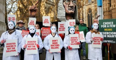 Protestors hold placards as they gather outside the Parliament as British lawmakers debate the assisted dying law, in London, Britain, Nov. 29, 2024. (Reuters Photo)