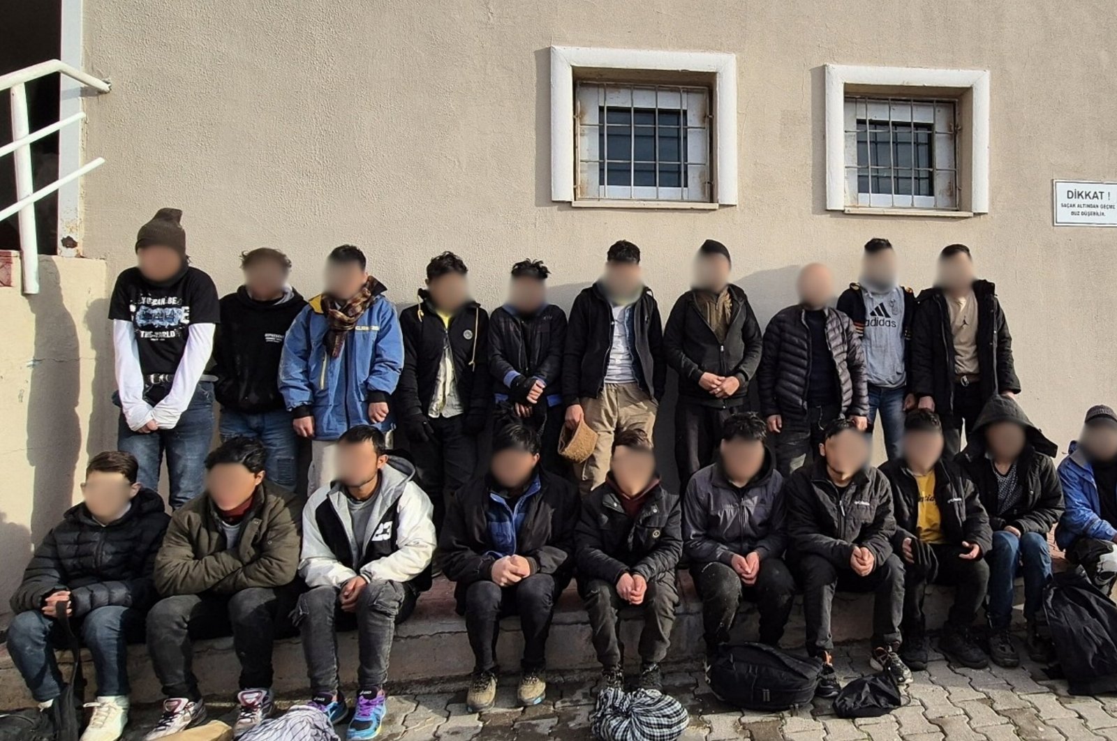 Some 20 irregular migrants stand outside a police station following their capture in eastern Van province, Türkiye, Nov. 28, 2024. (AA Photo)