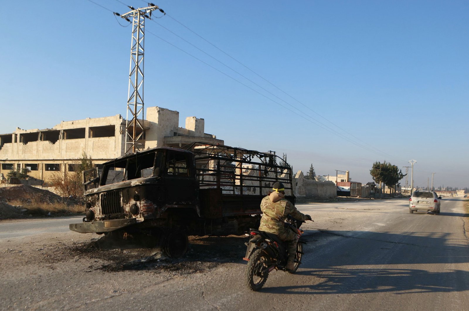 A fighter rides his motorbike past a burnt truck in Khan al-Assal, which was taken over by anti-regime forces led by Hayat Tahrir al-Sham (HTS) in the latest battles with regime forces in the northern Syrian province, Nov. 29, 2024. (AFP Photo)