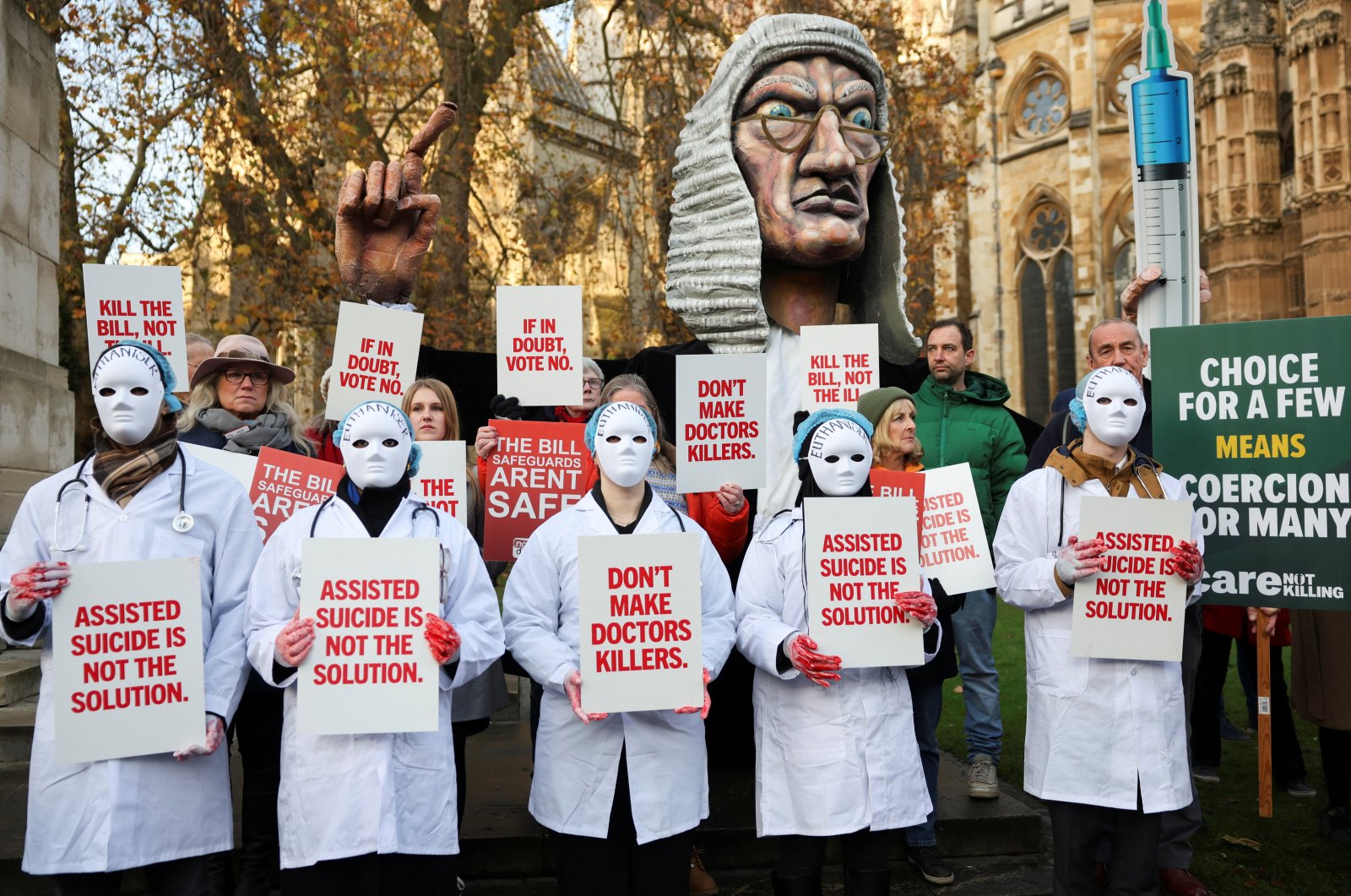 Protestors hold placards as they gather outside the Parliament as British lawmakers debate the assisted dying law, in London, Britain, Nov. 29, 2024. (Reuters Photo)