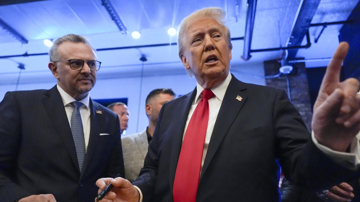 Former President Donald Trump signs autographs as Massad Boulos listens during a visit to The Great Commoner, in Dearborn, Michigan, U.S., Nov. 1, 2024. (AP Photo)