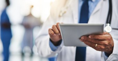 This cropped shot shows a doctor using a digital tablet with his colleagues in the background. (Reuters Photo)