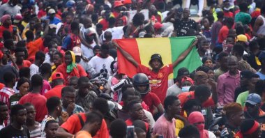 A supporter holds up a Guinean National Flag as exiled activists arrive at a football match, Conakry, Guinea, Sept. 18, 2021. (AFP Photo)
