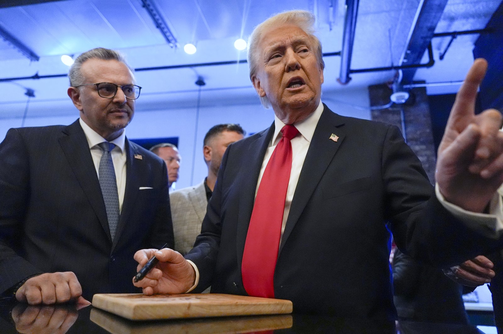 Former President Donald Trump signs autographs as Massad Boulos listens during a visit to The Great Commoner, in Dearborn, Michigan, U.S., Nov. 1, 2024. (AP Photo)