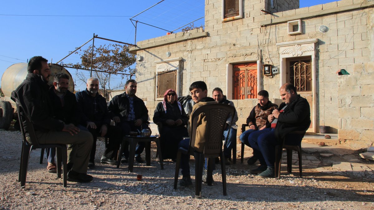 A family displaced by PKK/YPG terrorist group sits outside their home in Tal Rifaat after the region was liberated, northern Syria, Dec. 2, 2024. (AA Photo)