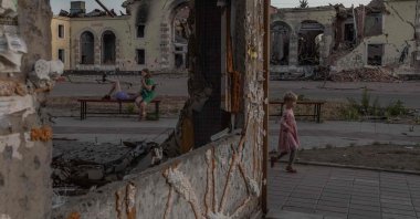 A child plays as women rest on a bench in front of residential buildings destroyed by shelling in Kostyantynivka, eastern Donetsk region, Ukraine, June 22, 2024. (AFP Photo)
