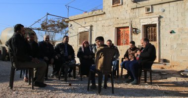 A family displaced by PKK/YPG terrorist group sits outside their home in Tal Rifaat after the region was liberated, northern Syria, Dec. 2, 2024. (AA Photo)