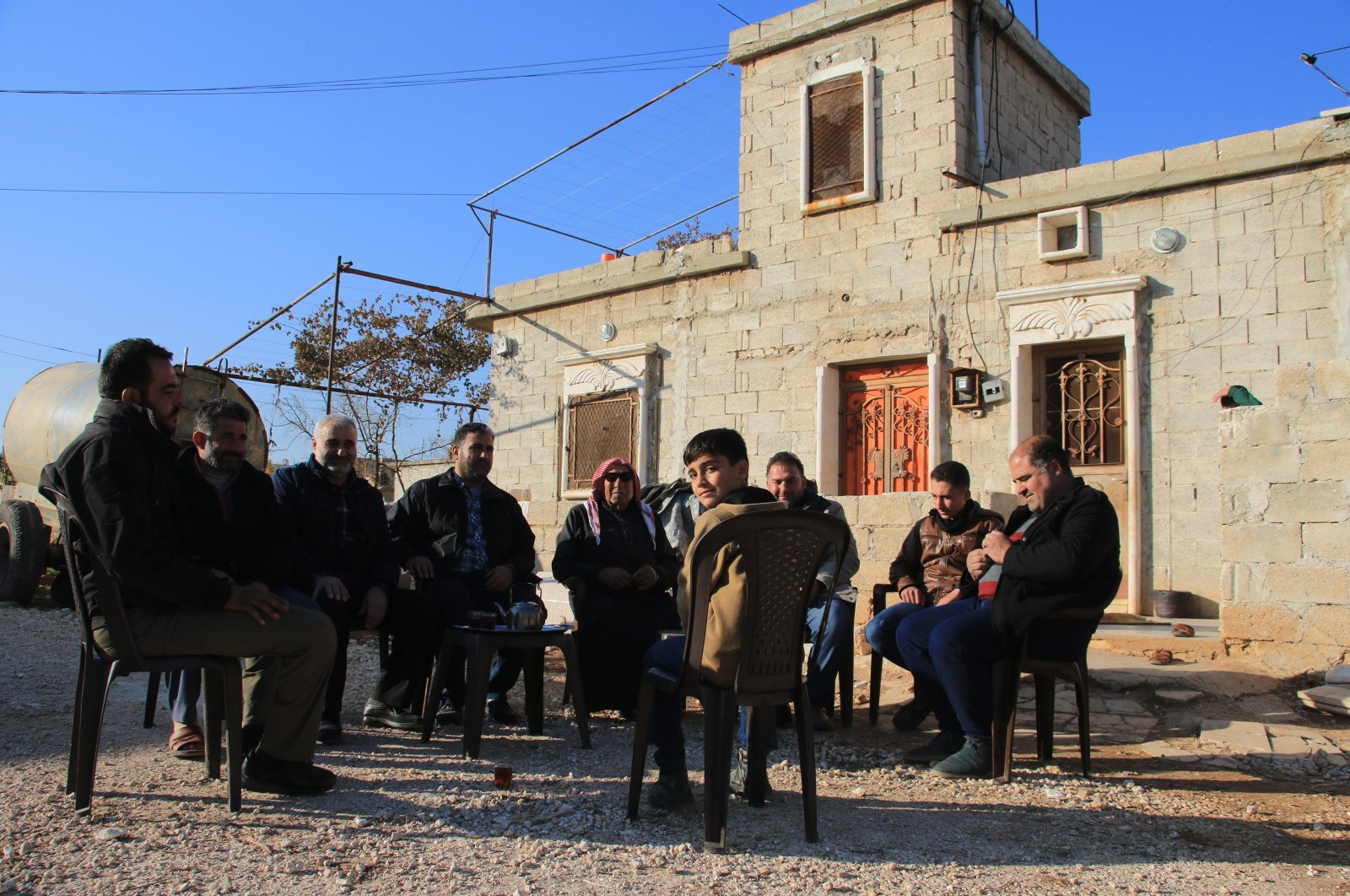 A family displaced by PKK/YPG terrorist group sits outside their home in Tal Rifaat after the region was liberated, northern Syria, Dec. 2, 2024. (AA Photo)