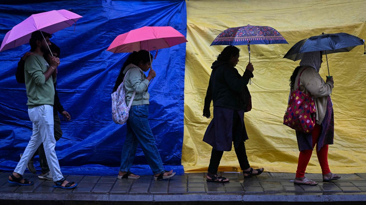 People holding umbrellas walk along a street as it rains due to the influence of Cyclone Fengal, a low-level cyclone that smashed into India&#039;s southern coastline and killed at least three people, Bengaluru, India, Dec. 1, 2024. (AFP Photo)