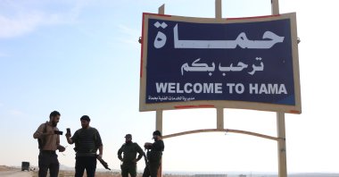 Members of anti-regime forces pose in front of a sign near Hama, Syria, Dec. 3, 2024. (AA Photo)