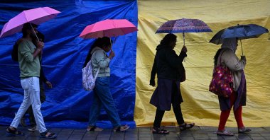 People holding umbrellas walk along a street as it rains due to the influence of Cyclone Fengal, a low-level cyclone that smashed into India&#039;s southern coastline and killed at least three people, Bengaluru, India, Dec. 1, 2024. (AFP Photo)