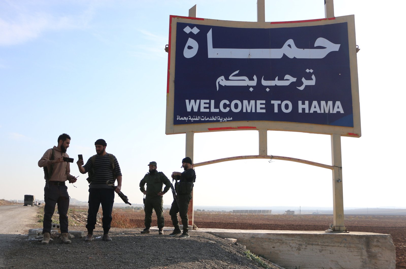 Members of anti-regime forces pose in front of a sign near Hama, Syria, Dec. 3, 2024. (AA Photo)