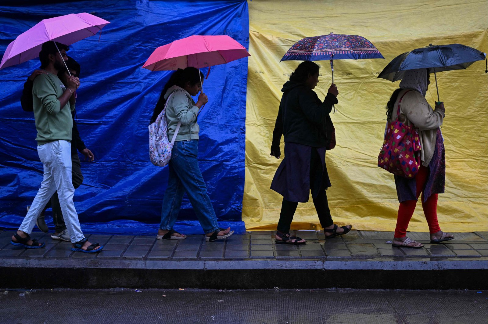 People holding umbrellas walk along a street as it rains due to the influence of Cyclone Fengal, a low-level cyclone that smashed into India&#039;s southern coastline and killed at least three people, Bengaluru, India, Dec. 1, 2024. (AFP Photo)