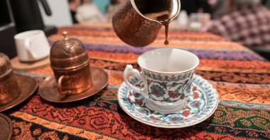 A Turkish coffee is poured from a &quot;cezve&quot; – a traditional long-handled pot used to brew coffee – into a classic coffee cup during the World Turkish Coffee Day event at the Yunus Emre Institute in Toronto, Canada, Dec. 5, 2024. (AA Photo)