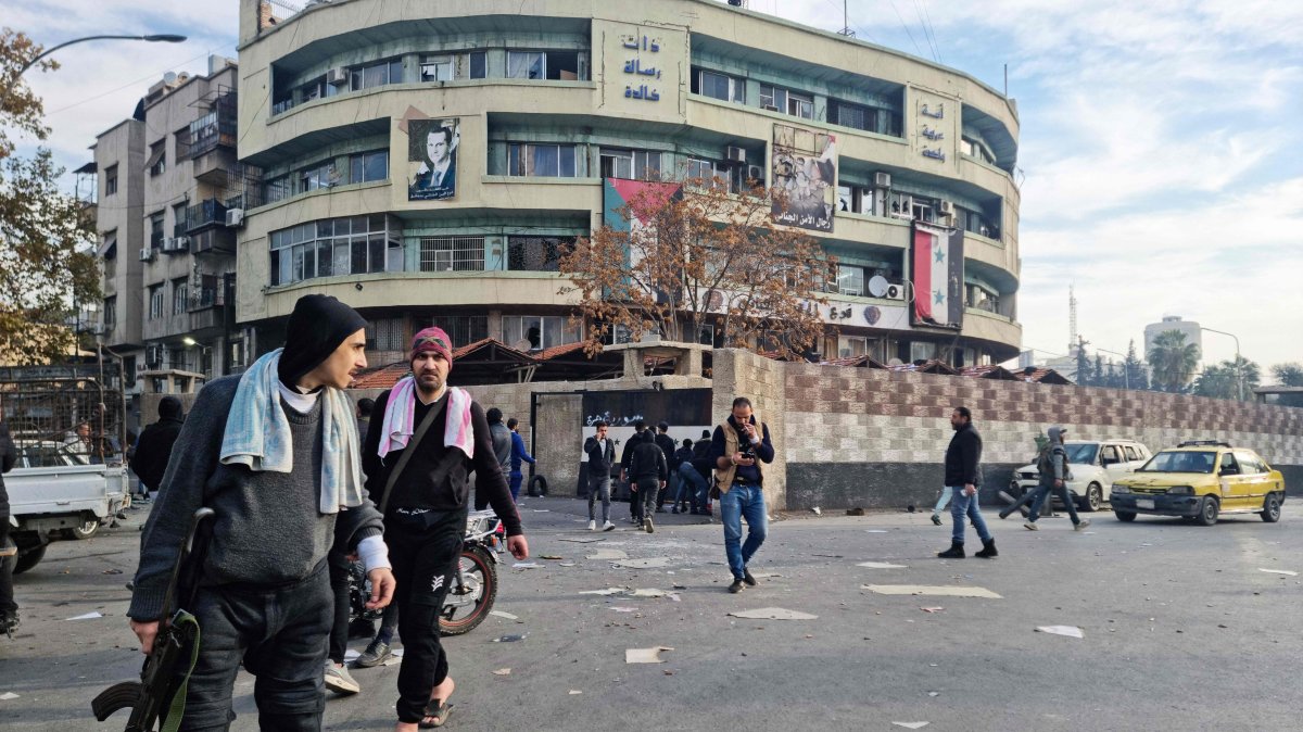 Anti-regime fighters walk in front of a government office building, Damascus, Syria, Dec. 8, 2024. (AFP Photo)