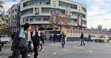 Anti-regime fighters walk in front of a government office building, Damascus, Syria, Dec. 8, 2024. (AFP Photo)