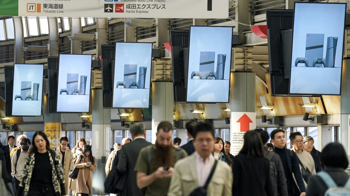 People walk past digital signage advertising Sony&#039;s limited edition PlayStation 5 Pro console at the Shinagawa Station, Tokyo, Japan, Dec. 3, 2024. (EPA Photo)