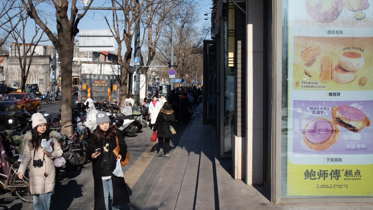 People walk near a shop selling food in Beijing, China, Dec. 9, 2024. (EPA Photo)