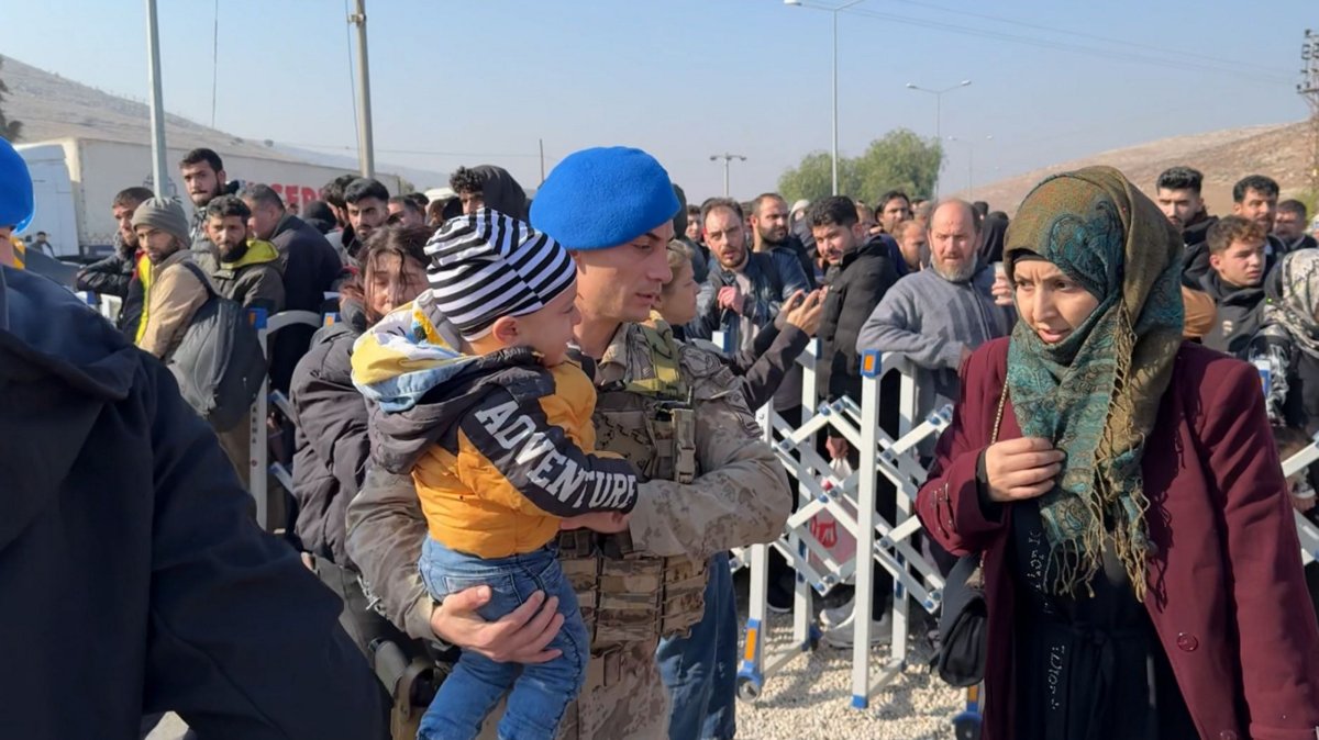 A Turkish soldier at the border assists a Syrian family as they arrive at the Cilvegözü Border Gate to return home after Assad&#039;s fall, Hatay, southeastern Türkiye, Dec. 9, 2024. (AA Photo)