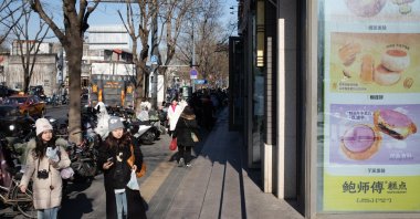 People walk near a shop selling food in Beijing, China, Dec. 9, 2024. (EPA Photo)