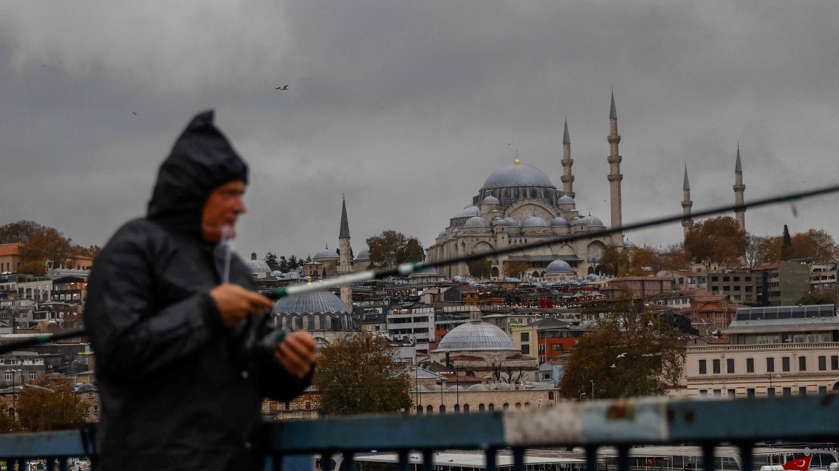 A man fishes on Galata Bridge during heavy rain in Istanbul, Türkiye, Nov. 21, 2024. (AFP Photo)