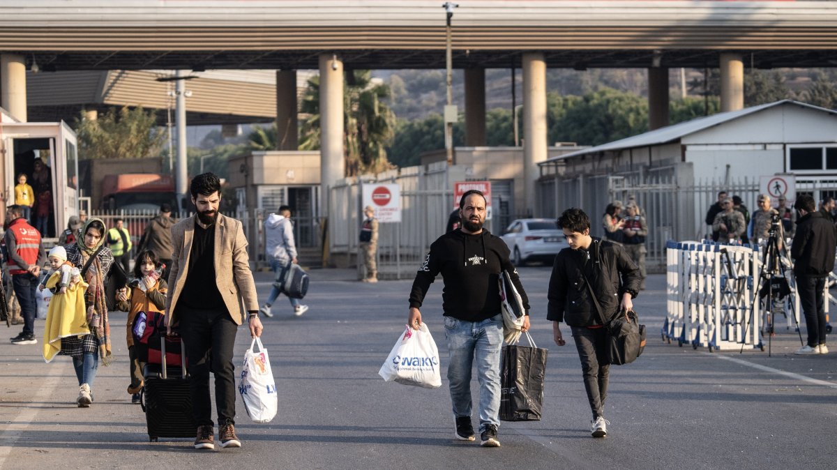 Syrians walk with their belongings on the Turkish side of the Cilvegözu Border Gate, between Türkiye and Syria, in the Reyhanli district of Hatay, Türkiye, Dec. 10, 2024. (EPA Photo)