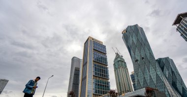 A pedestrian passes close to the skyscraper office buildings, part of Istanbul Financial Center (IFC), Istanbul, Türkiye, May 9, 2023. (Getty Images Photo)