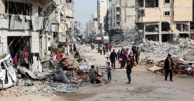 People walk past the rubble of collapsed and damaged buildings along a street in Gaza City, Dec.11, 2024. (AFP Photo)