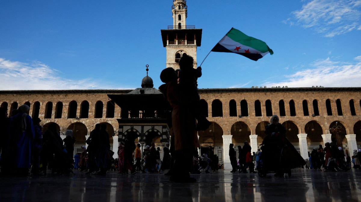 A child holds a flag adopted by the Syrian new rulers following the ouster of longtime dictator Bashar Assad in Damascus, Syria, Dec. 12, 2024. (Reuters Photo)