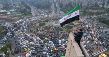 An aerial view shows a Syrian man waving the independence-era Syrian flag at Damascus' central Umayyad Square, Syria, Dec. 11, 2024. (AFP Photo)