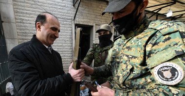 A soldier from the Salvation Government (R) collects the weapon of a former security guard of the Baath party offices, Damascus, Syria, Dec. 12, 2024. (AFP Photo)