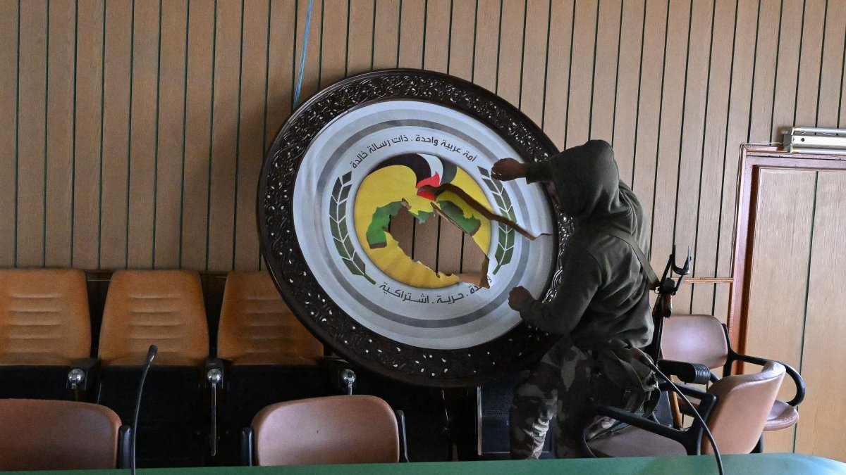 An anti-regime fighter breaks a sign at the Baath party offices, Damascus, Syria, Dec. 12, 2024. (AFP Photo)