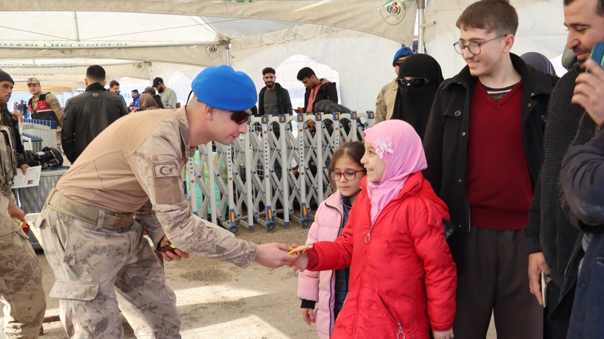 A Turkish soldier offers a candy bar to a Syrian girl returning home with her family through a border crossing in Hatay, southeastern Türkiye, Dec. 13, 2024. (AA Photo)