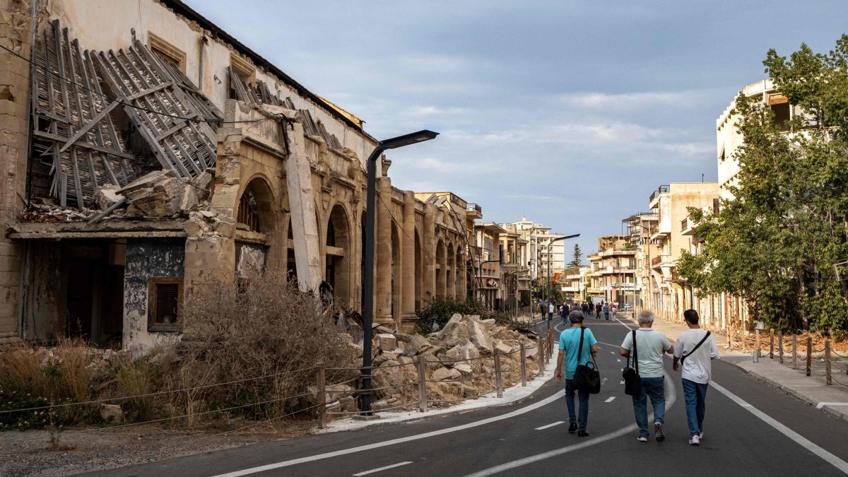 Journalists walk during an organized tour past partially collapsed abandoned buildings in Varosha (Maraş), in the fenced-off area of Famagusta, TRNC, June 19, 2023. (AFP Photo)