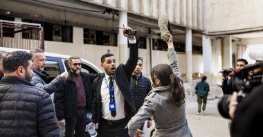 An angry woman looking for her missing brother and two of her cousins waves a shoe in front of the car of U.N.'s special envoy to Syrian during a visit at the Sadnaya prison in Damascus, Dec. 16, 2024. (AFP Photo)