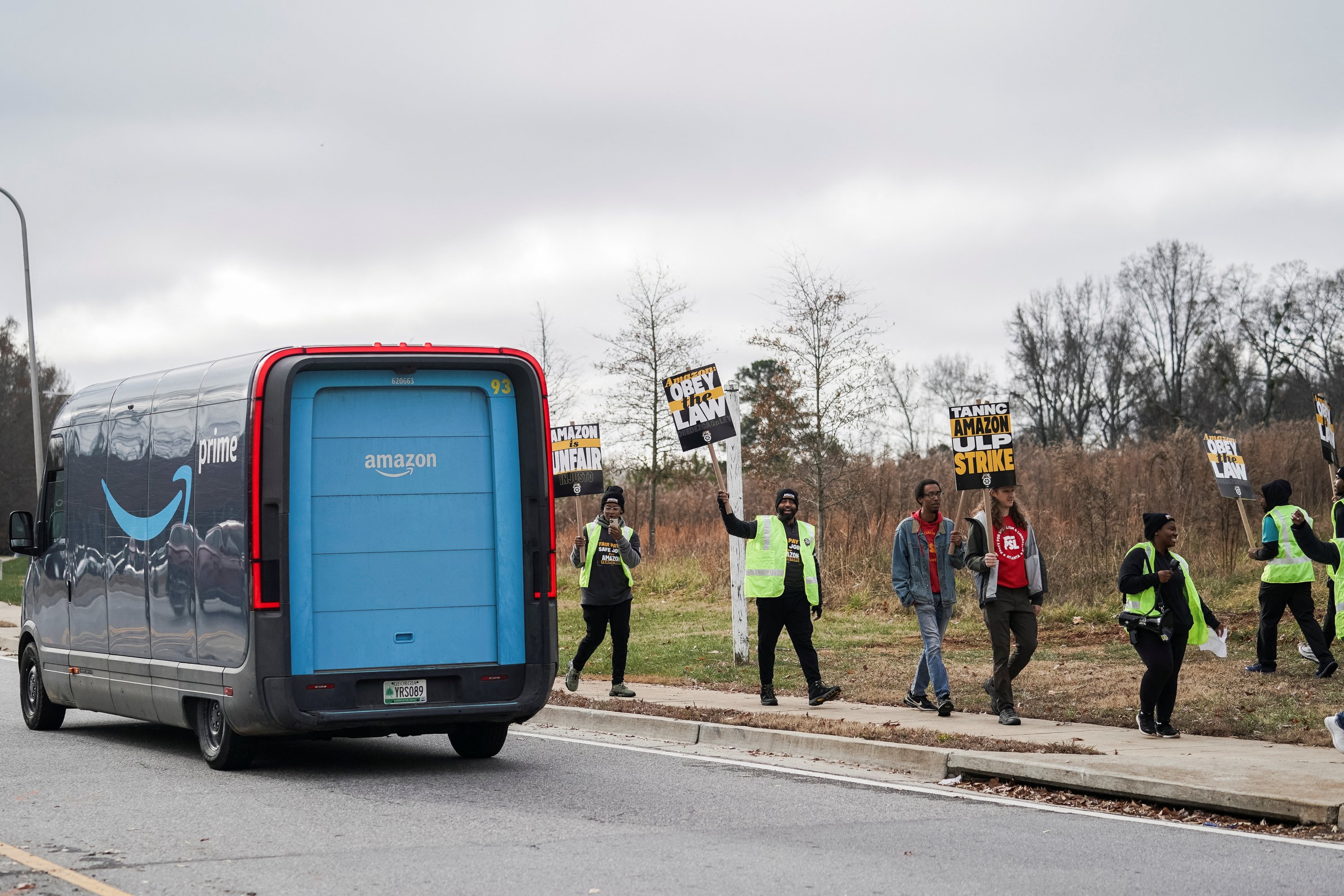 An Amazon delivery truck passes people holding signs and marching during a strike by Teamsters union members at an Amazon facility in Alpharetta, Georgia, U.S., Dec. 19, 2024. (Reuters Photo)