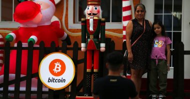 People pose for a picture near Christmas season decorations with a sign displaying the Bitcoin logo in San Salvador, El Salvador, Dec. 9, 2024. (Reuters Photo)
