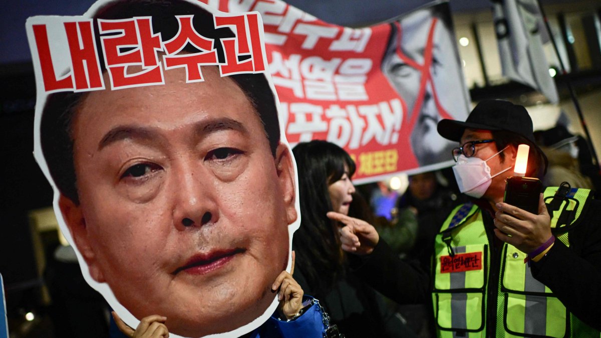 A protester holding a cardboard reading "Leader of insurgents" on an image depicting the face of South Korea&#039;s President Yoon Suk Yeol takes part in a protest calling for his ouster outside the National Assembly, Seoul, South Korea, Dec. 8, 2024. (AFP Photo)