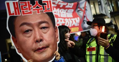 A protester holding a cardboard reading "Leader of insurgents" on an image depicting the face of South Korea&#039;s President Yoon Suk Yeol takes part in a protest calling for his ouster outside the National Assembly, Seoul, South Korea, Dec. 8, 2024. (AFP Photo)