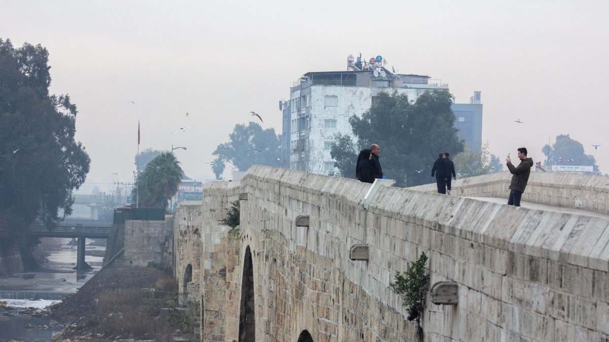 People walk across Taşköprü Bridge on a rainy winter day, Adana, Türkiye, Dec. 22, 2024. (IHA Photo)