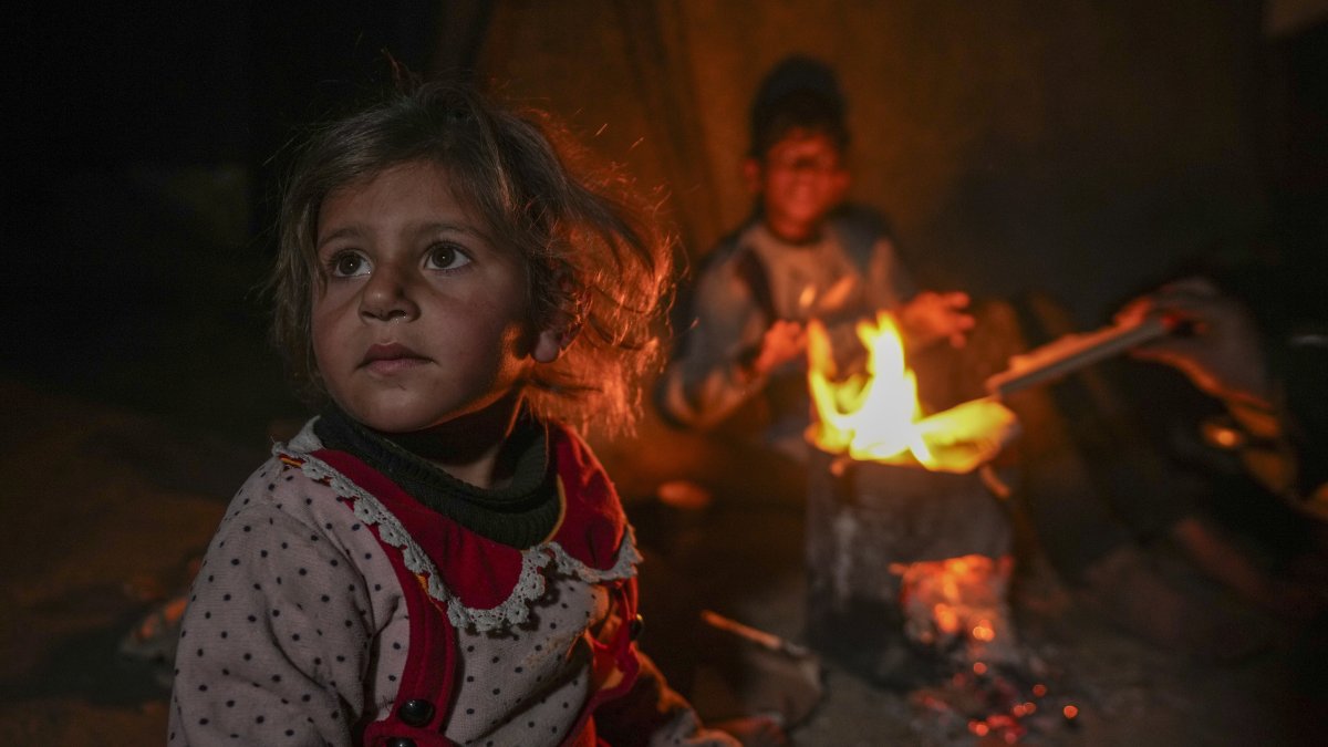 The grandchildren of Reda Abu Zarada sit by a fire at a camp by the sea in Khan Younis, Gaza Strip, Dec. 19, 2024. (AP Photo)