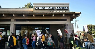 Starbucks workers hold signs as they picket during a strike in front of a Starbucks to demand collective bargaining agreements, Burbank, California, U.S., Dec. 20, 2024. (AFP Photo)