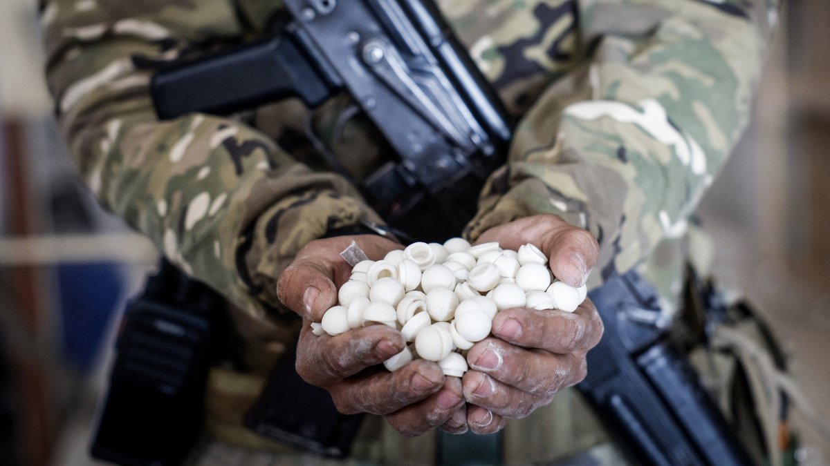 A soldier holds empty capsules used in packaging an illicit drug called Captagon (the brand name of psychostimulant drug Fenethylline), which were discovered hidden inside mothballs at the warehouse where the drug was produced before the ouster of the Assad regime, Damascus, Syria, Dec. 20, 2024. (EPA Photo)