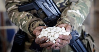 A soldier holds empty capsules used in packaging an illicit drug called Captagon (the brand name of psychostimulant drug Fenethylline), which were discovered hidden inside mothballs at the warehouse where the drug was produced before the ouster of the Assad regime, Damascus, Syria, Dec. 20, 2024. (EPA Photo)