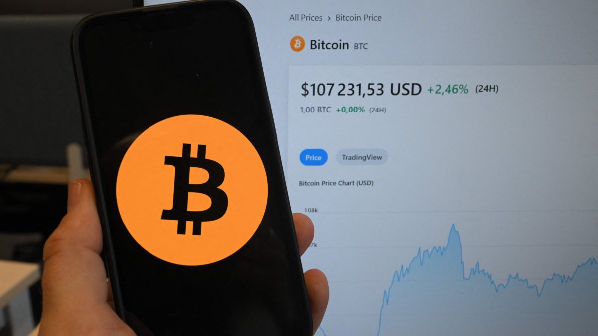 This illustration photograph shows the bitcoin cryptocurrency logo displayed on a smartphone beside a screen showing a trading chart, Brussels, Belgium, Dec. 17, 2024. (AFP Photo)